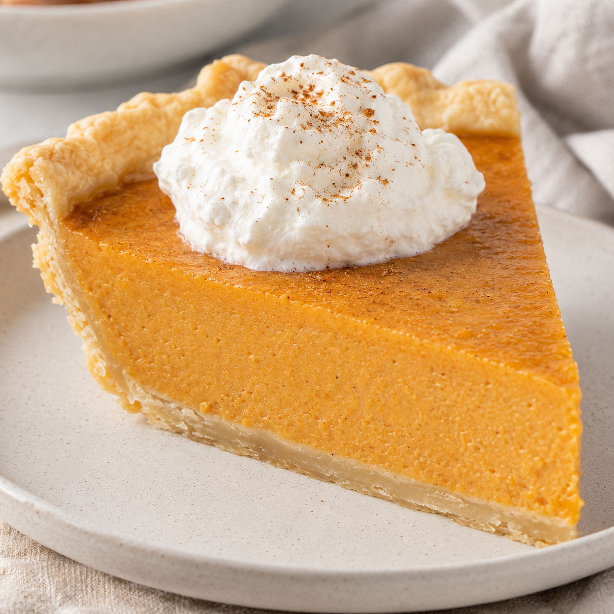 Sweet potato pie slice with whipped cream and golden flaky crust