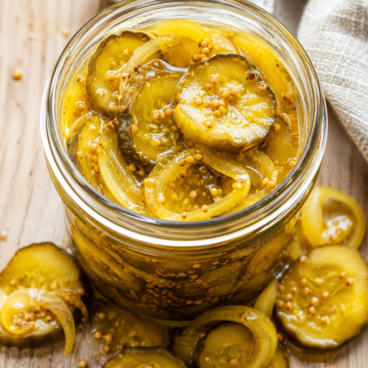 Tangy bread and butter pickles with golden brine in a glass mason jar