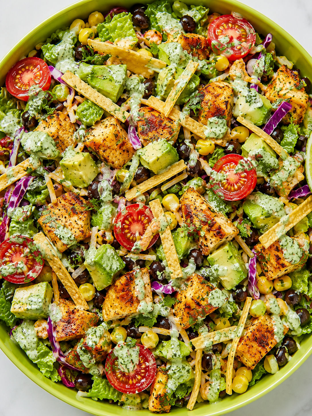Overhead Tex-Mex taco chicken chopped salad with avocado, corn, and crispy tortilla strips in a bowl