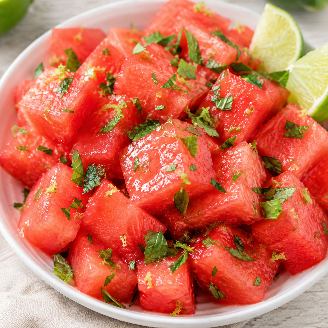 Watermelon salad with lime, mint, and lime zest in a white bowl