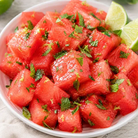 Watermelon salad with lime, mint, and lime zest in a white bowl