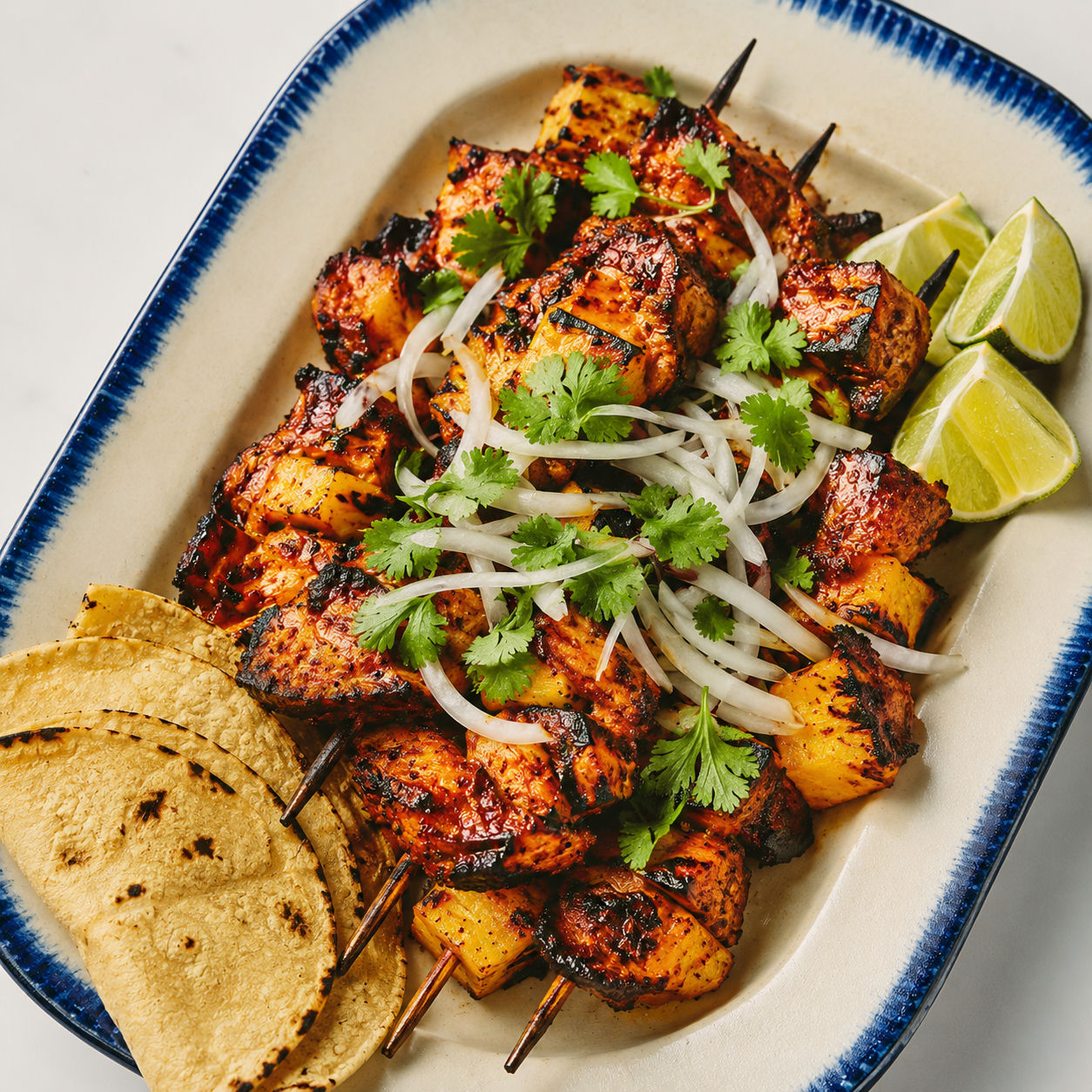 Al pastor chicken skewers with pineapple, cilantro, onion, and lime