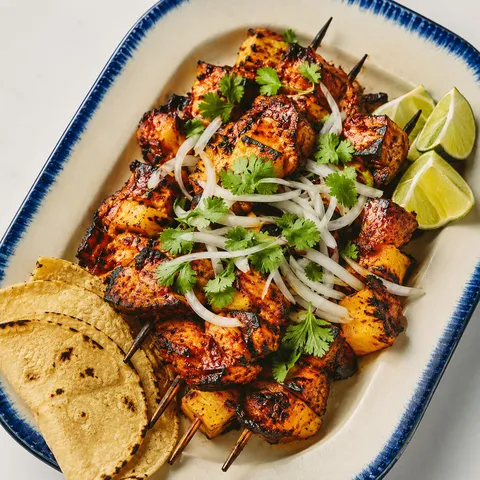 Al pastor chicken skewers with pineapple, cilantro, onion, and lime