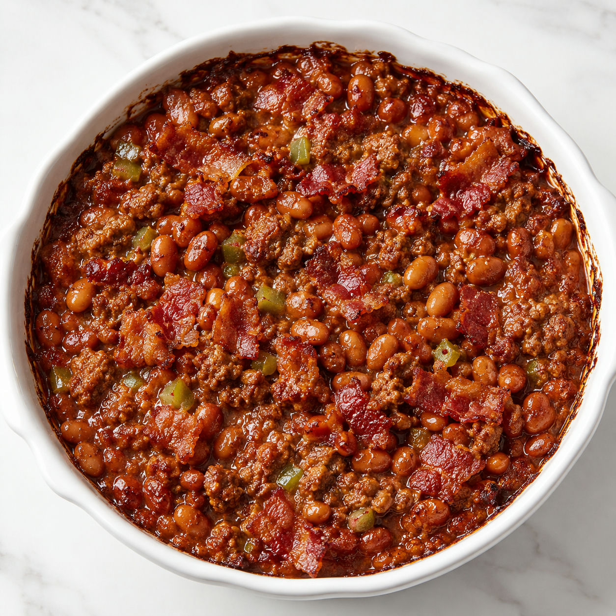 Baked beans and ground beef casserole with bacon in a white dish