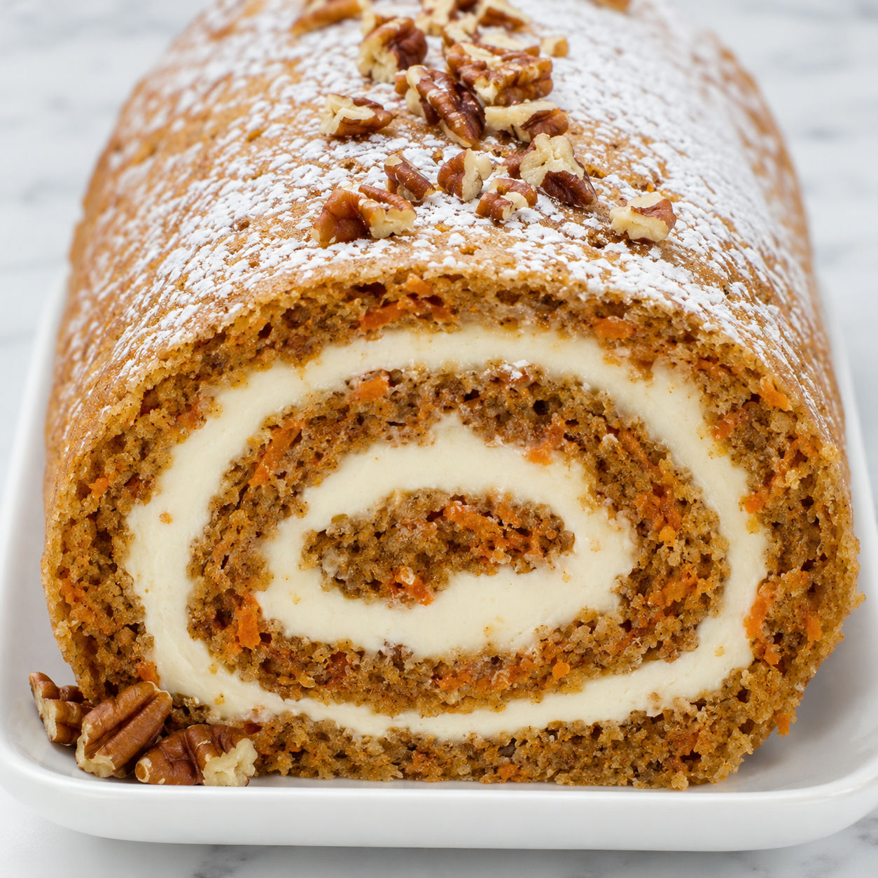 Sliced carrot cake roll with cream cheese filling and powdered sugar