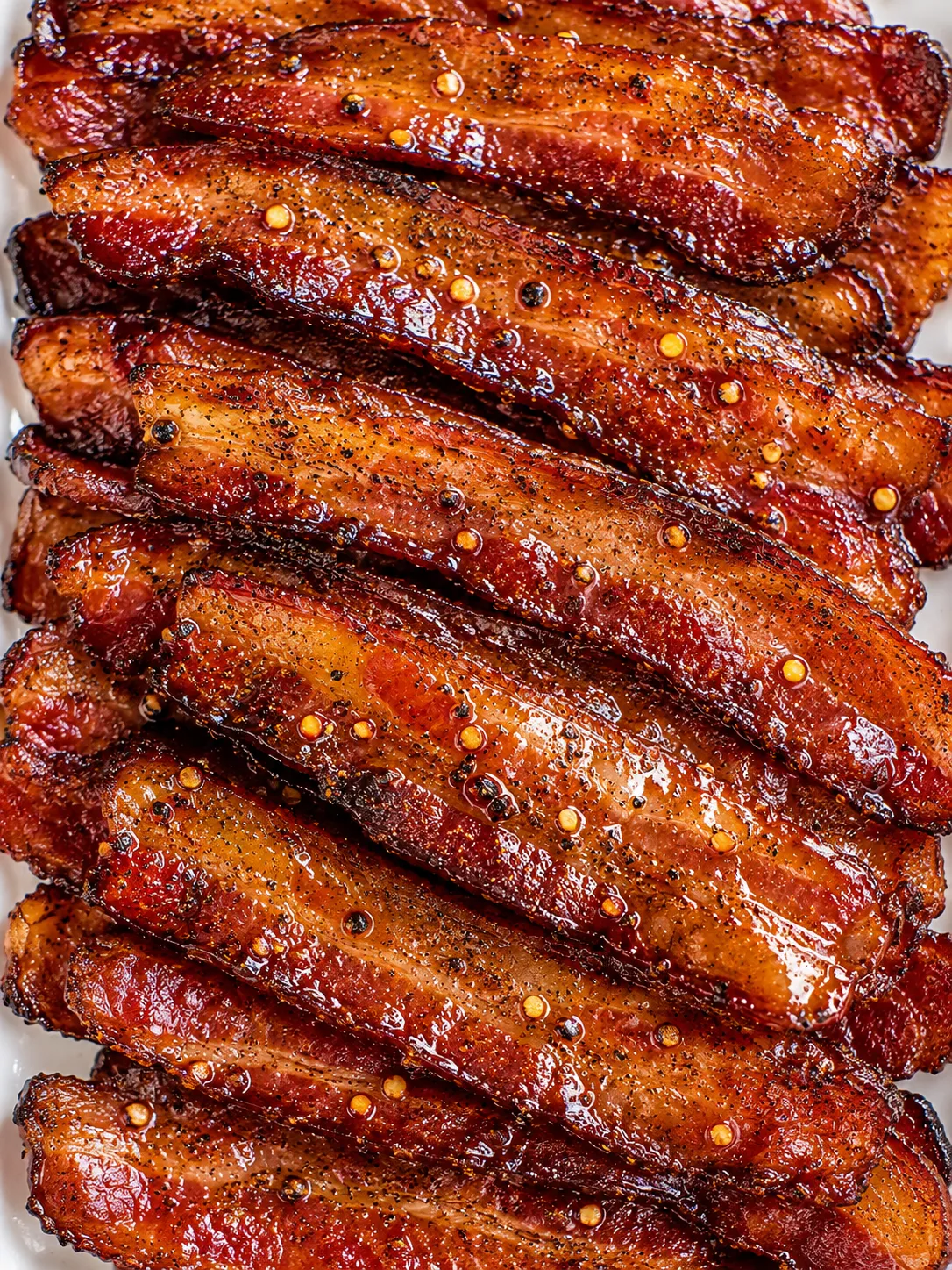 Maple pepper candied bacon stacked on a white platter