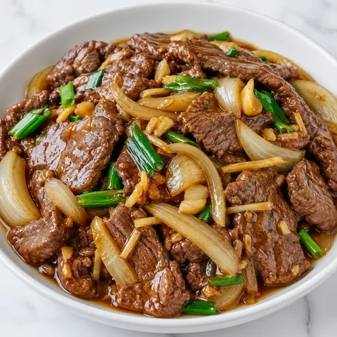 Oyster sauce beef and onion stir-fry with scallions in a white bowl