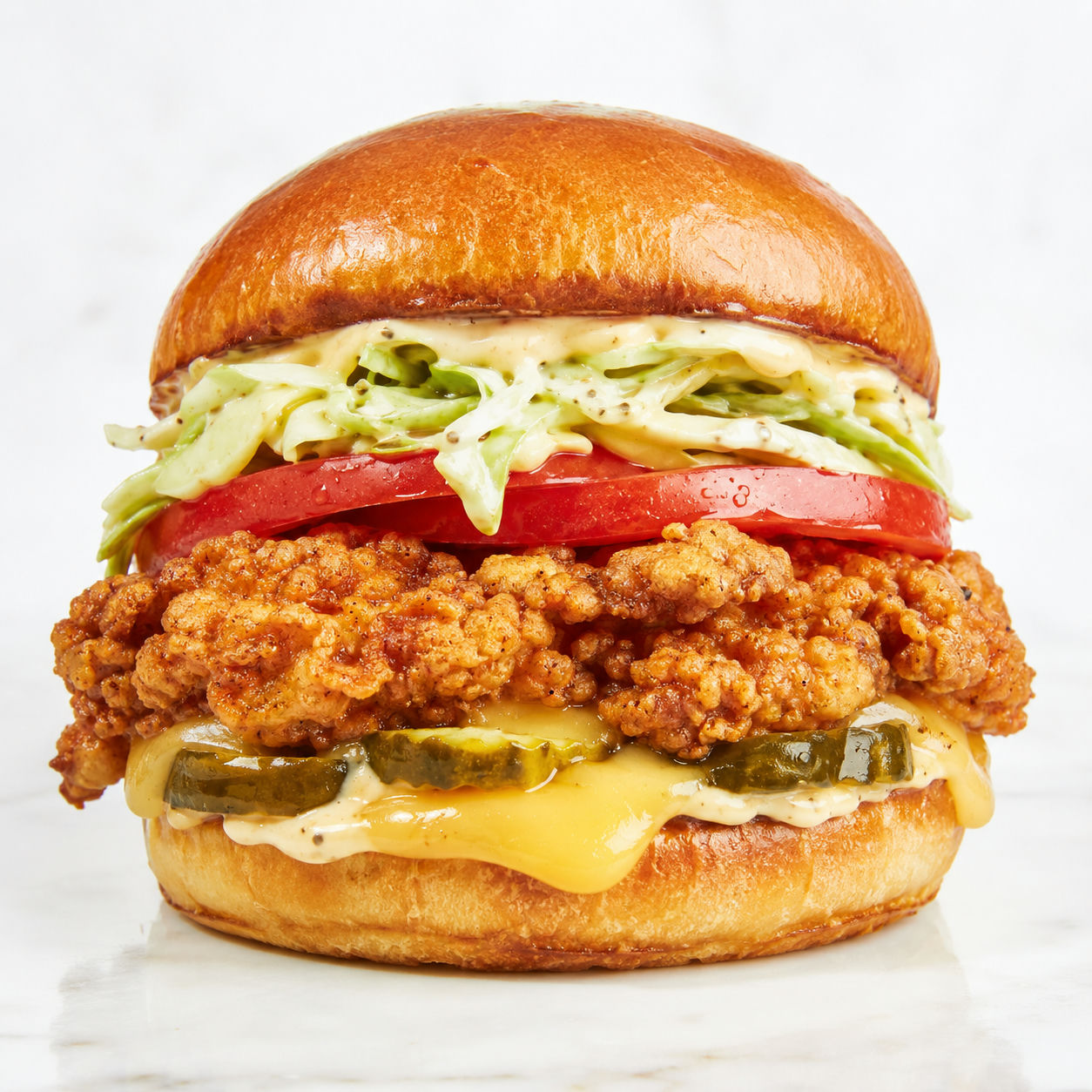 Crispy chicken sandwich with gouda, pickles, slaw, and honey pepper mayo