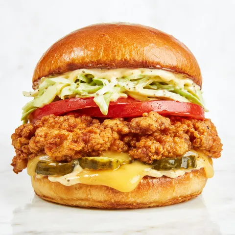Crispy chicken sandwich with gouda, pickles, slaw, and honey pepper mayo