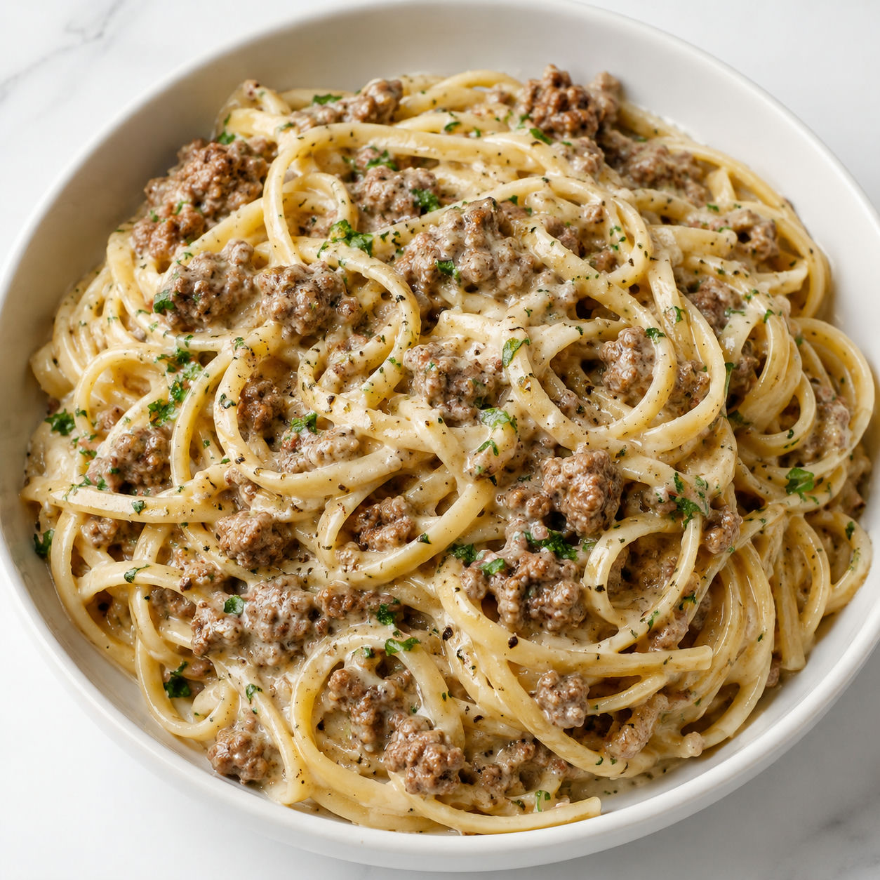 Creamy Parmesan ground beef linguine with parsley in a white bowl
