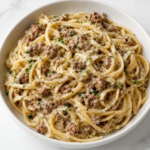 Creamy Parmesan ground beef linguine with parsley in a white bowl
