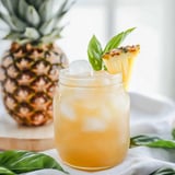 A glass of pineapple juice with a pineapple slice in it.