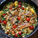 A black bowl filled with rice, tomatoes, and chicken.