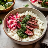 A bowl of rice with meat and sauce.