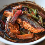 A bowl of food with a fish and vegetables.