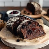 A loaf of bread with chocolate chips on top is displayed on a wooden table.