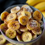 A bowl of bananas with sugar on top.