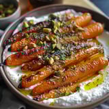 A bowl of food with carrots and white sauce.