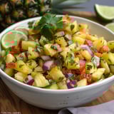 A bowl of fruit salad with pineapple, onions, and limes.