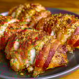 A plate of bacon wrapped chicken with a spice rub.