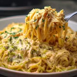 A bowl of creamy pasta with chicken and herbs.