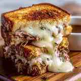 A French Dip sandwich is cut in half and served on a wooden cutting board.