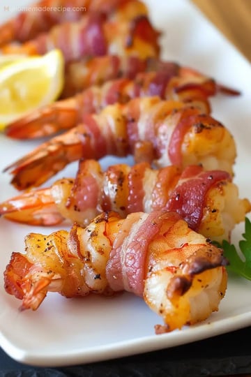 A plate of crispy bacon-wrapped shrimp garnished with lemon wedges