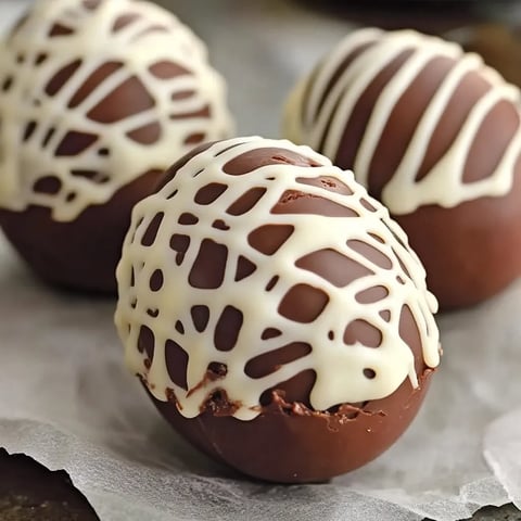 Three chocolate covered marshmallows on a table.