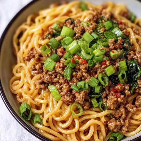 A bowl of Garlic Chicken Lo Mein Stir Fry with green onions and red peppers.