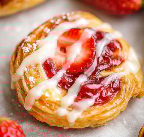 A sweet pastry topped with strawberries and fluffy cream, looks like a strawberry danish.
