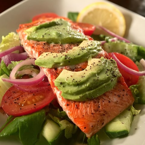 A delicious salmon avocado salad with a variety of fresh vegetables and a tangy dressing.