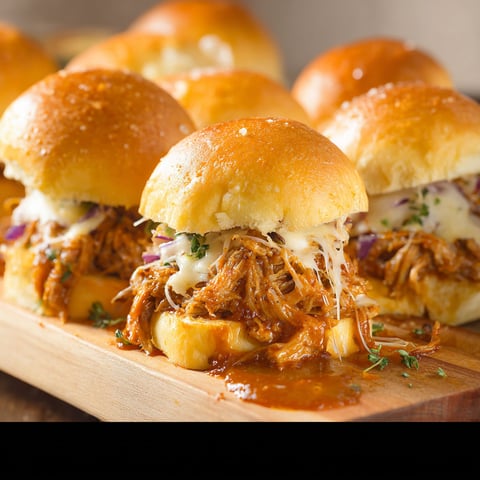 A plate of Pulled Pork Sliders with cheese and onions.