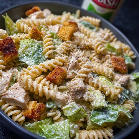 A bowl of delicious pasta salad with chicken, lettuce, and croutons.