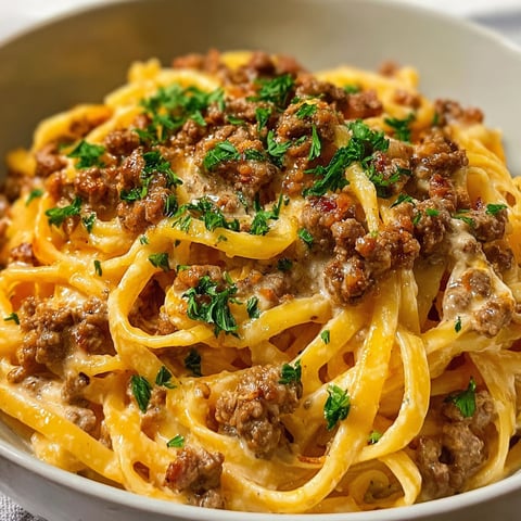 A bowl of pasta with ground beef and creamy Parmesan sauce.
