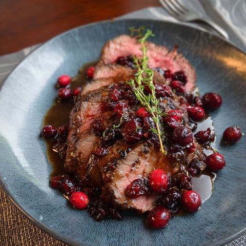 A plate of roast beef with cranberries and a balsamic glaze.
