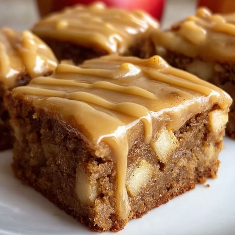 A delicious dessert, Apple Brownies with Maple Glaze, is displayed on a white plate.