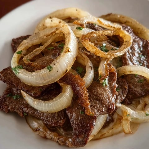 A plate of beef liver and onions, with onions on top.