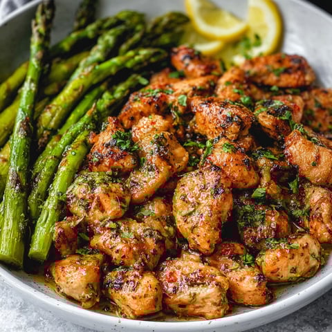 A plate of garlic butter chicken bites with asparagus.