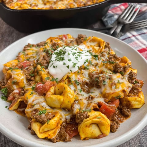 A delicious Cheesy Beef Enchilada Tortellini dish served in a white bowl.