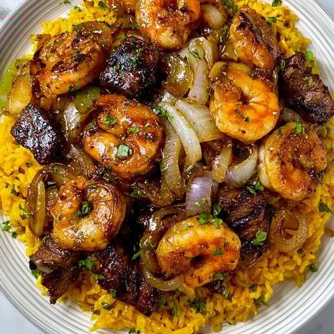 A plate of jerk steak and shrimp over tropical pilaf rice.