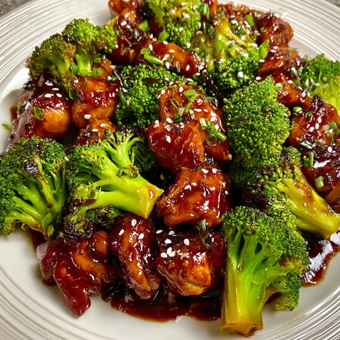 A plate of bourbon chicken with broccoli on top.