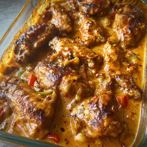 A dish of smothered chicken wings in a glass dish.