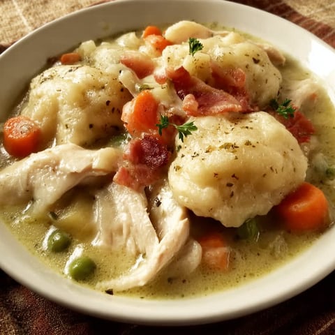 A bowl of Slow Cooker Chicken and Dumplings is served on a table.