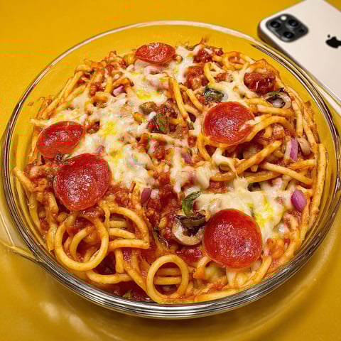 A bowl of spaghetti with pepperoni and cheese, ready to be eaten.